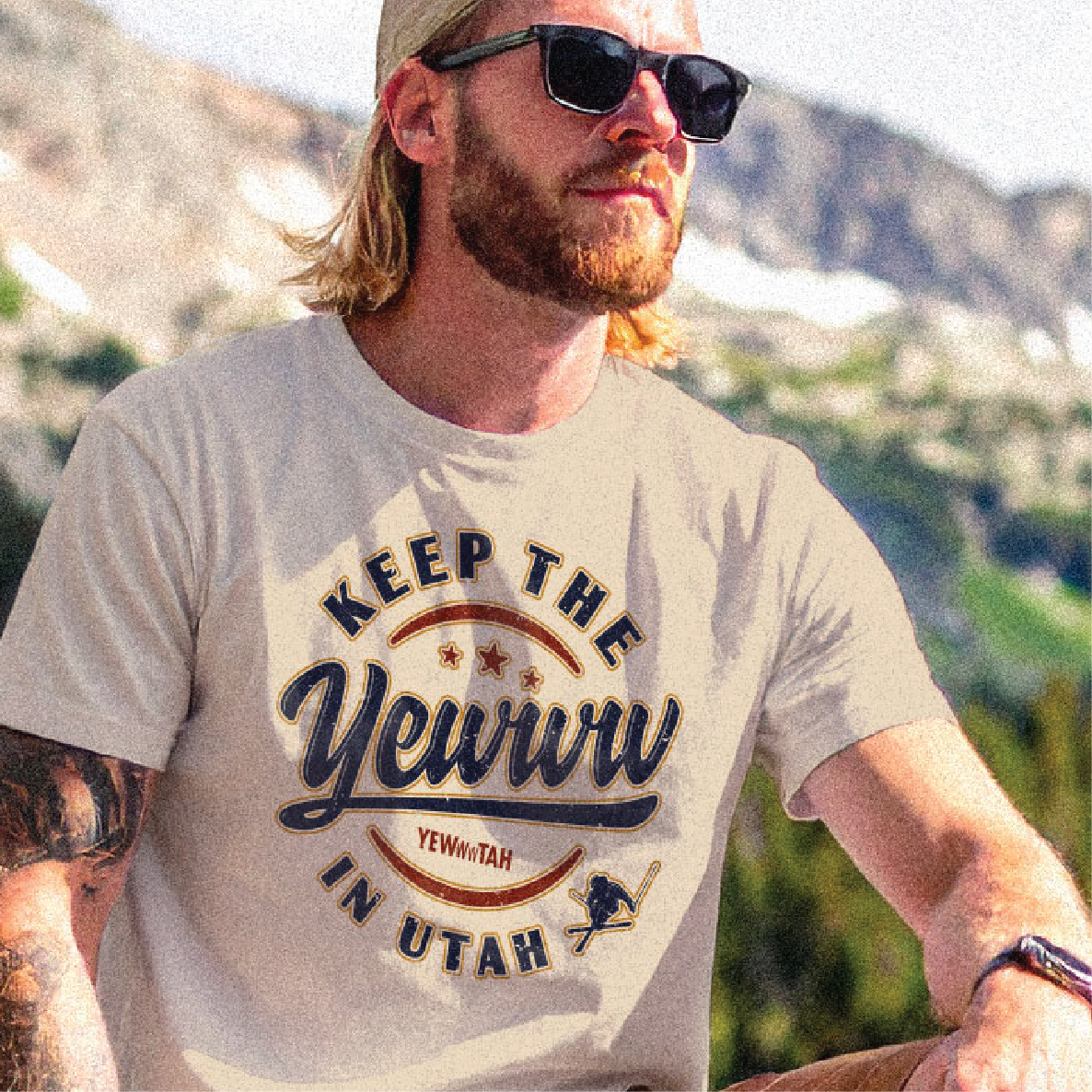 Man wearing sunglasses and a t-shirt with 'Keep the Yewww in Utah' text outdoors.