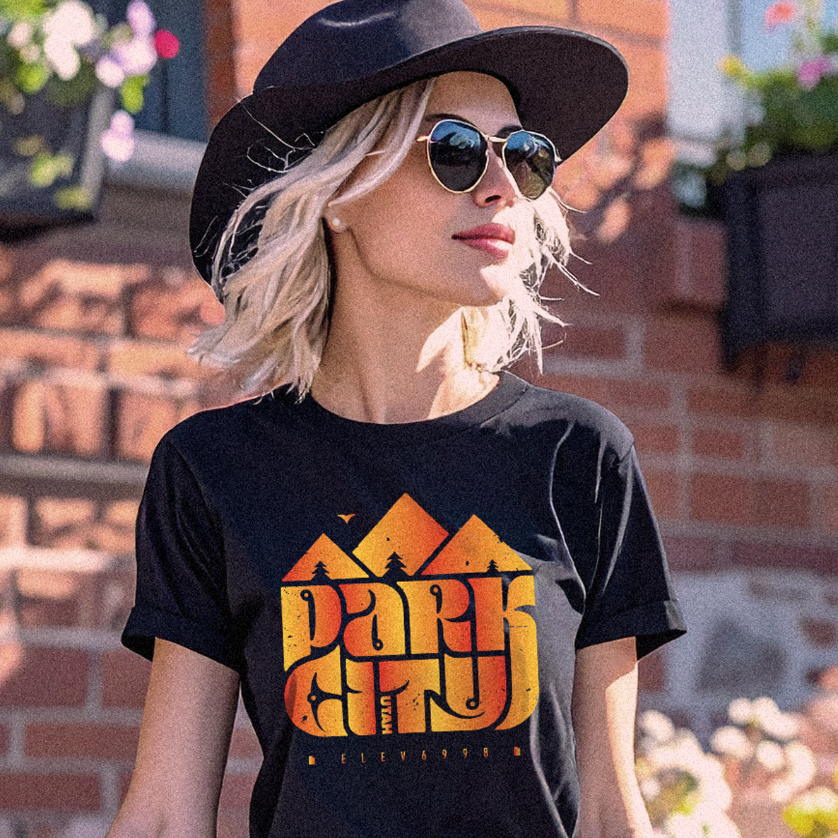 Woman wearing a black t-shirt with 'Park City' graphic design outdoors.