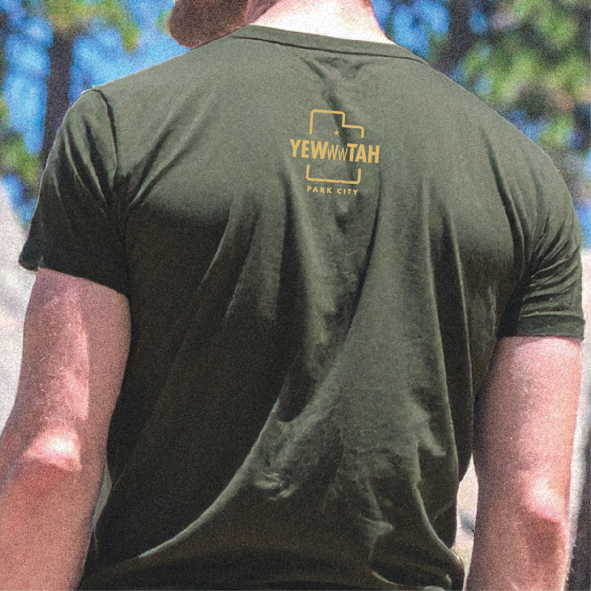 Person wearing a green t-shirt with 'Yewwwtah - Park City' logo on the back, standing outdoors.