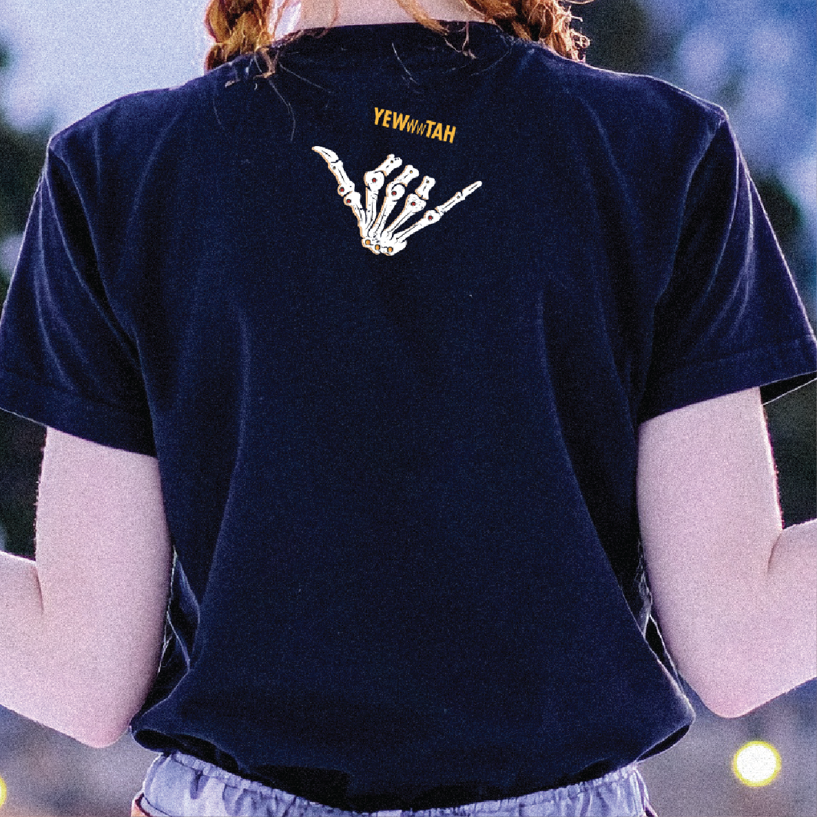 Person wearing a black t-shirt with a skeleton hand design and text on the back that says 'YEWWWTAH'