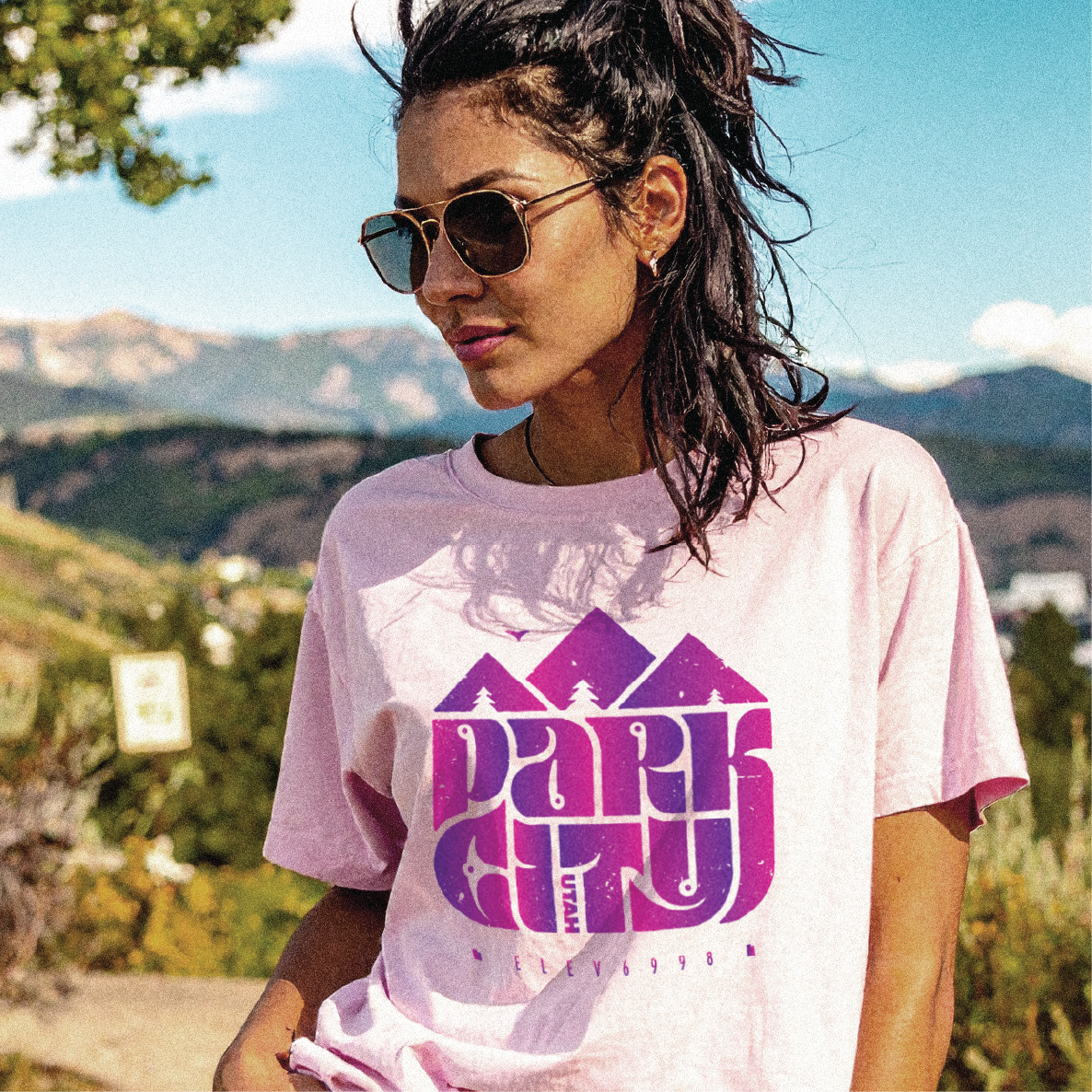 Woman wearing a pink t-shirt with 'Park City' design outdoors in Park City, UT