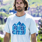 Man wearing a light blue t-shirt with a mountain graphic and Park City text outdoors.