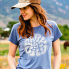 Woman wearing a blue t-shirt with 'Park City' graphic in a natural setting