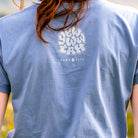 Person wearing a blue t-shirt with a "Yewwwtah" logo on the back, standing outdoors.