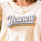 Beige t-shirt with 'Yewwwtah' graphic design featuring rainbow colors.