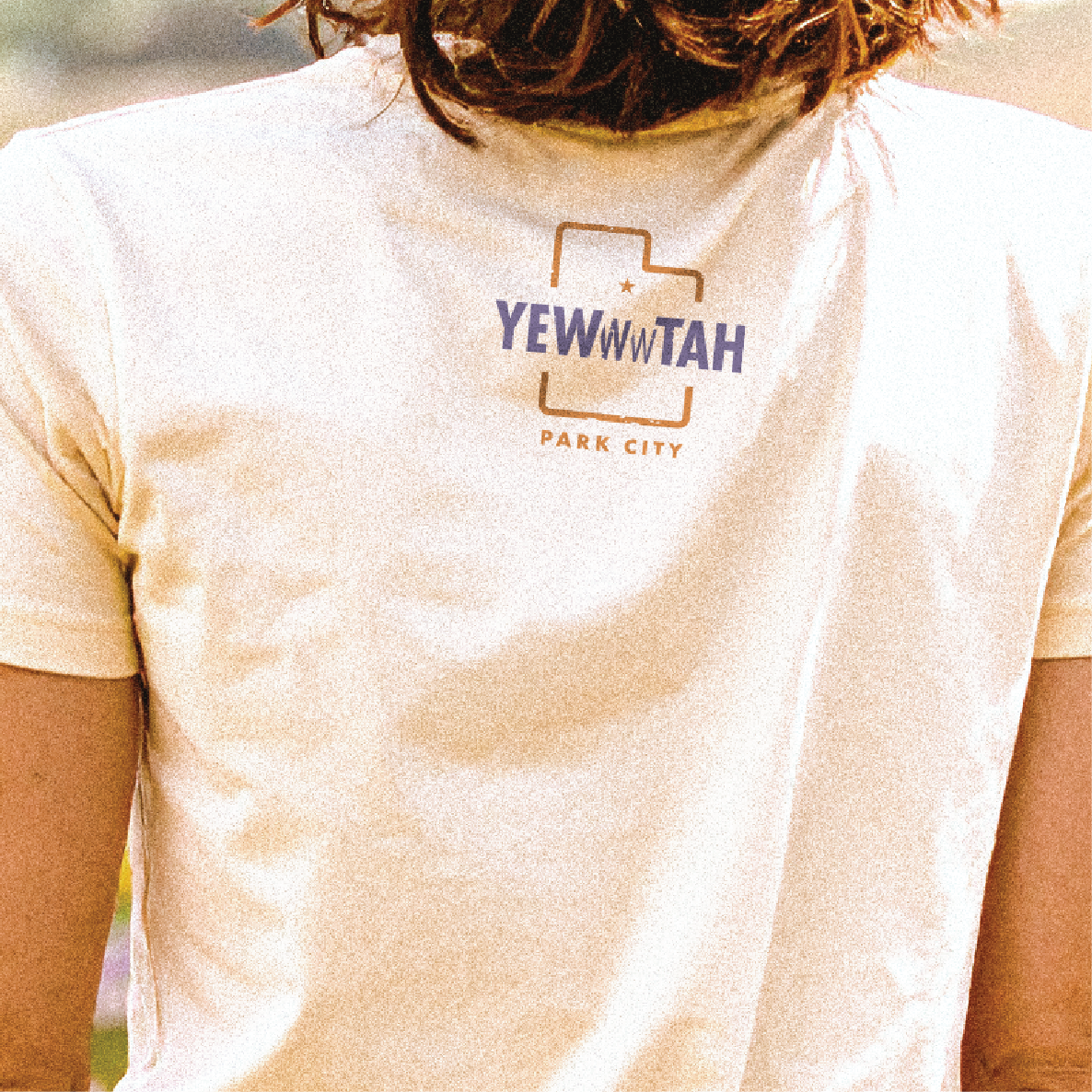 Person wearing a white t-shirt with 'YEW N' TAH Park City' printed on it.