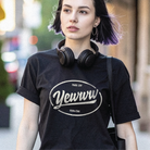 Woman wearing a black t-shirt with an ovular 'Yewww' logo, standing outdoors.