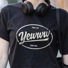 Person wearing a black t-shirt with oval 'Yewww' logo and Park City text, standing outdoors.