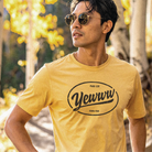 Man wearing a yellow t-shirt with an oval 'Yewww' logo outdoors