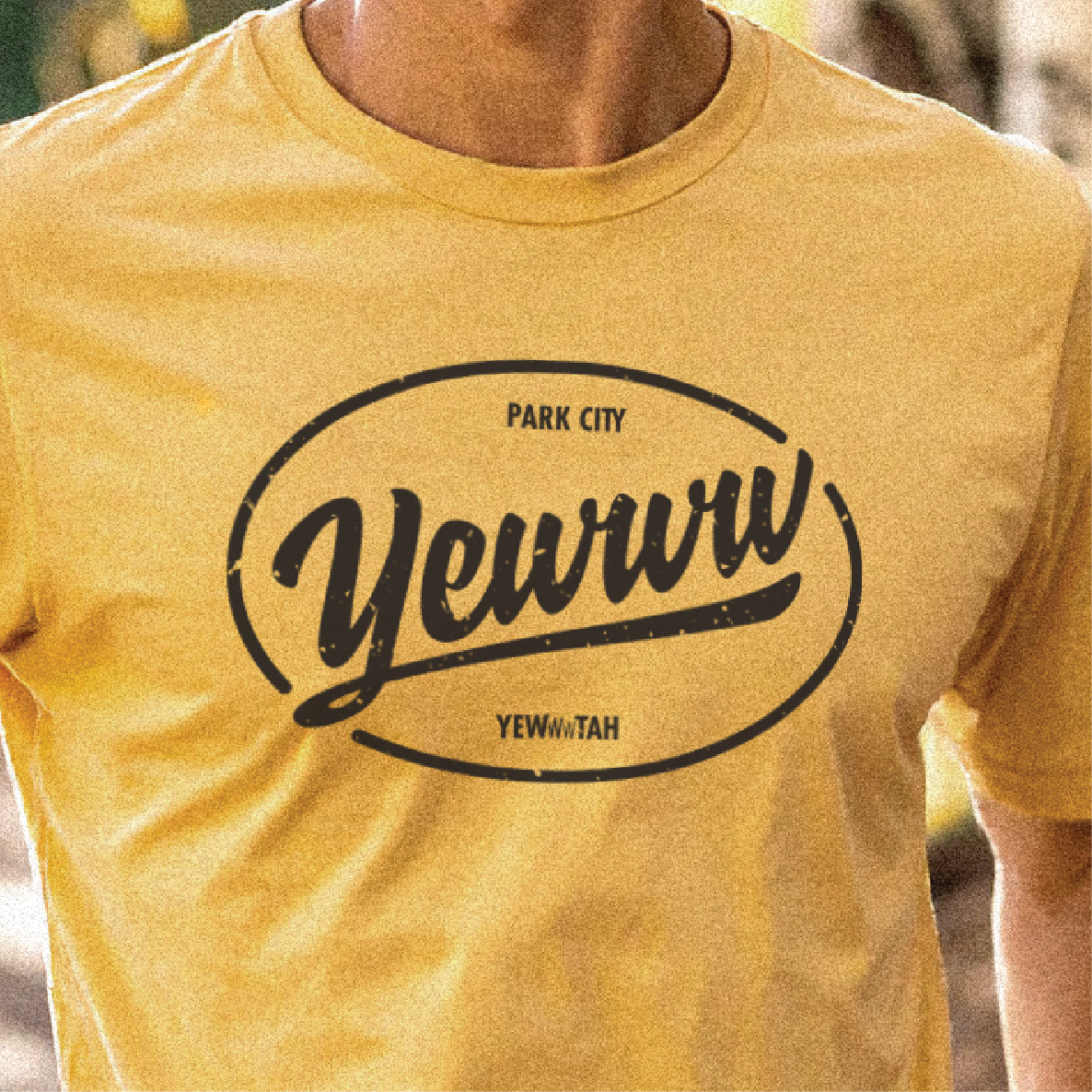 Yellow t-shirt with 'Yewww Park City Yewwwtah' text on a blurred background